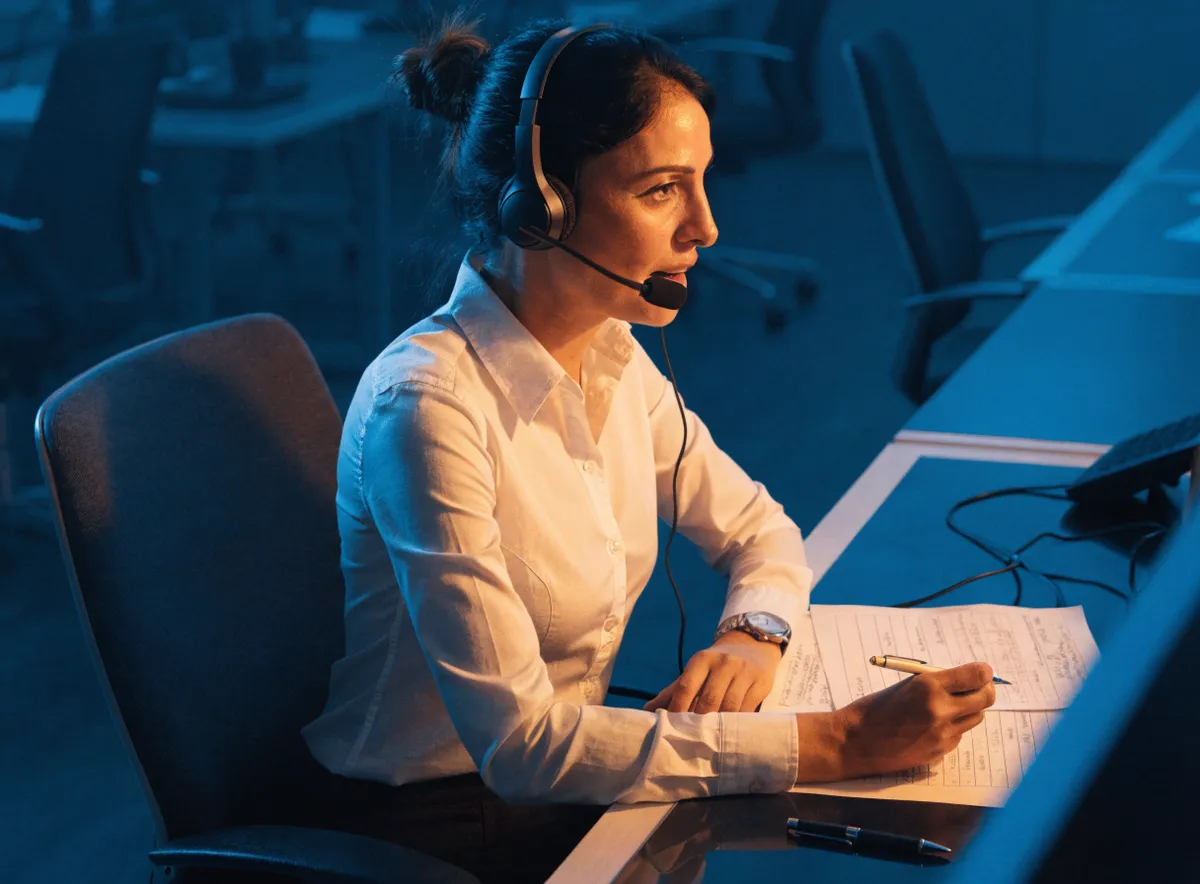 Encuestadora profesional administrando un cuestionario de estudio de mercado por teléfono en un contact center