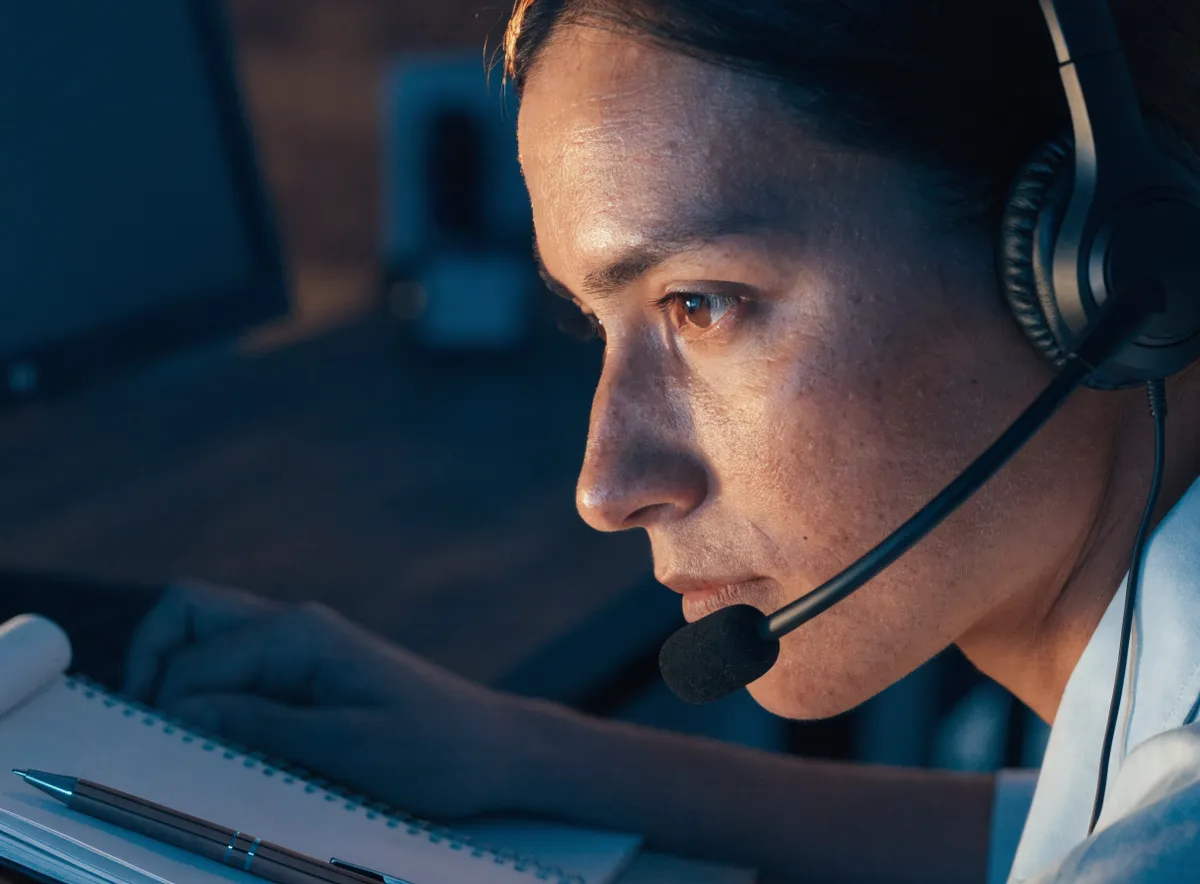 Agente de contact center durante el manejo de objeciones en ventas telefónicas B2B en un puesto de trabajo
